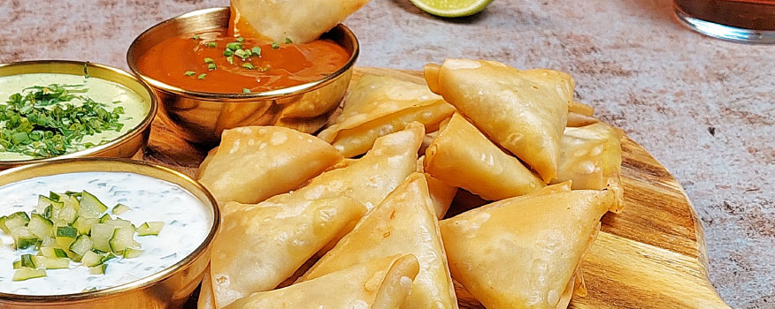 Mini samosas de pollo al curry con tres salsas indi